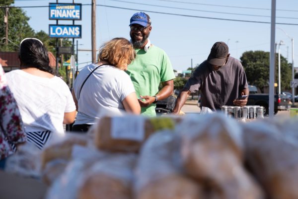Bridgewood Church of Christ member Booker Williams, center, greets neighbors during the congregation's regular Saturday food giveaway.