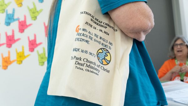 An attendee carries a National Deaf Christian Workshop bag.