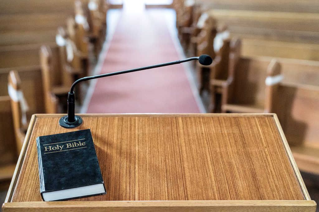 Bible on church pulpit, with view over the empty pews in the church