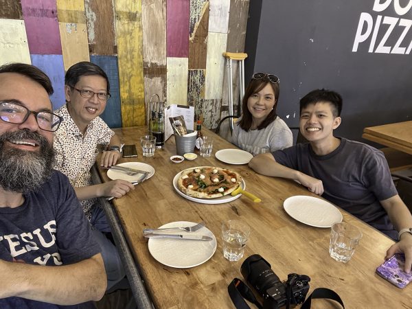 Erik Tryggestad eats pizza in Singapore with minister John Lim and his parents.